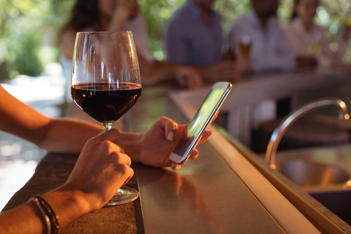 Wine glass on a bar while smartphone displays shoppable wine video content and digital marketing call to action