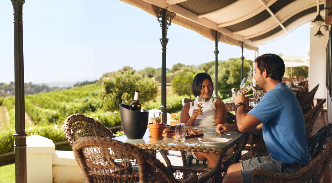 couple wine tasting outside next to vineyard