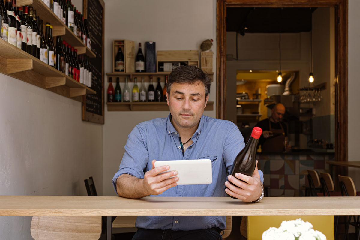 winery worker working on tablet while checking wine inventory