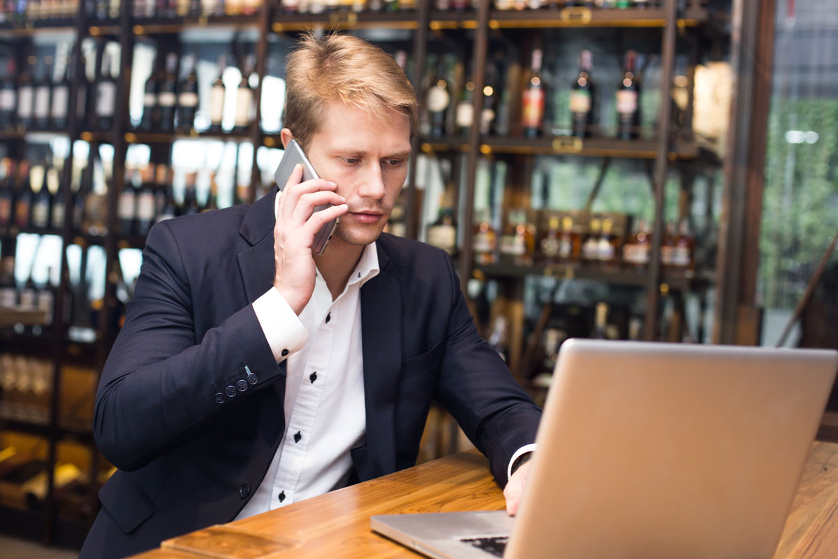 man in winery using laptop and phone